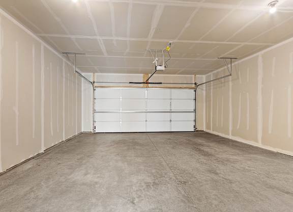 A sparsely furnished garage with a white door and a concrete floor.