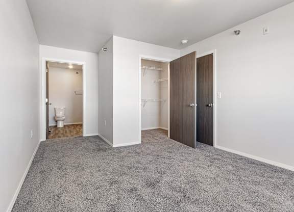 A room with a carpeted floor and two doors.