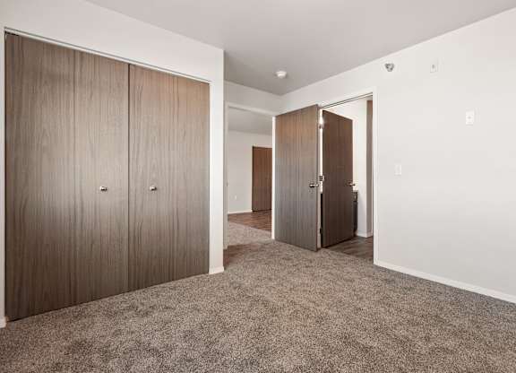A room with a carpeted floor and two wooden doors.