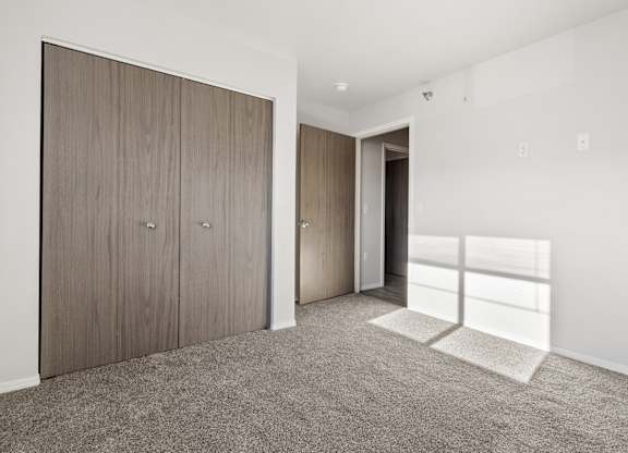 A room with a carpeted floor and a wooden door.