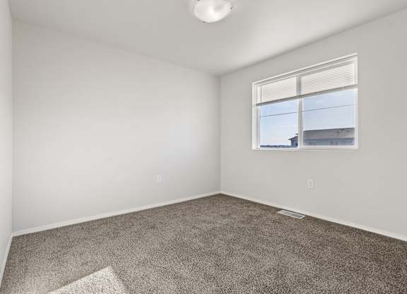 A room with a carpeted floor and a window.
