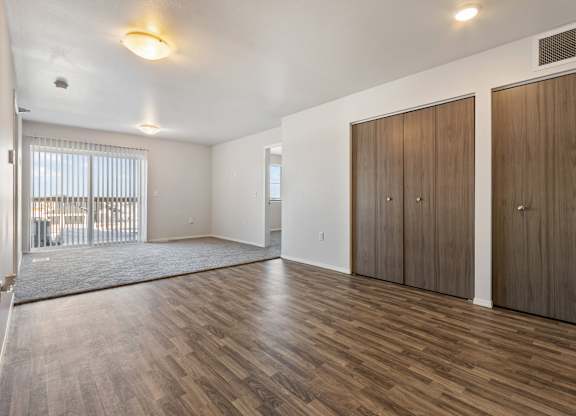 A room with wooden floors and two brown wardrobes.
