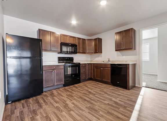 A kitchen with wooden floors and brown cabinets.