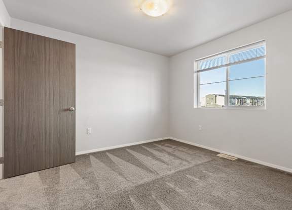 A room with a carpeted floor and a large window.