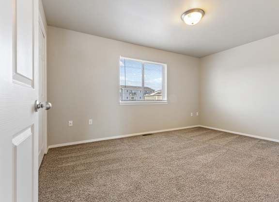 A room with a carpeted floor and a window showing a view of a building outside.