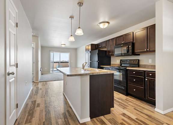 A kitchen with black appliances and brown cabinets.
