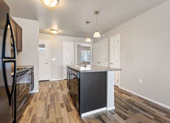 A kitchen with a black island and wooden floors.