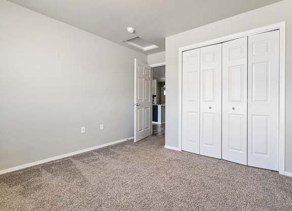 A room with white walls and a carpeted floor with a white door on the right.