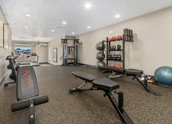 A gym with a variety of equipment including weights and a bench.