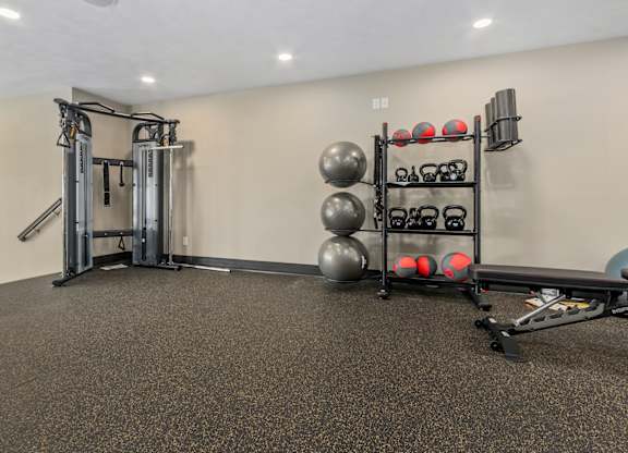 A gym with a weight bench, a rack of weights and a wall with a sign.