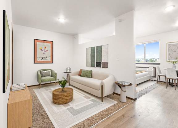 A living room with a white couch, a green chair, and a wooden table.