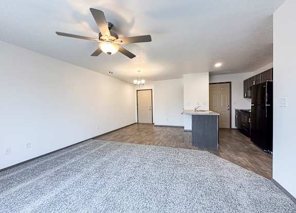 A room with a ceiling fan and a grey carpet.