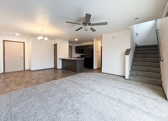 A spacious living room with a staircase on the right side.