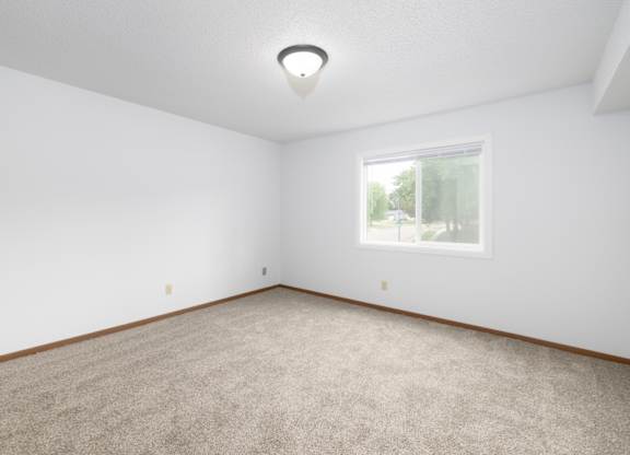 A room with a carpeted floor and a window.