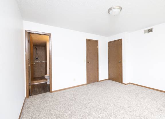 A room with a carpeted floor and two doors.