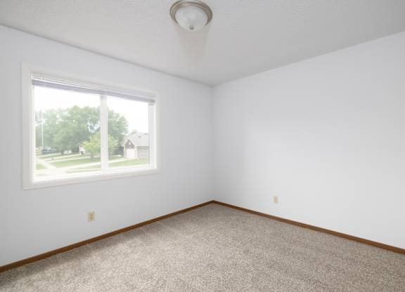A room with a carpeted floor and a window.
