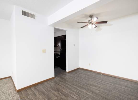 A room with a ceiling fan and wooden flooring.