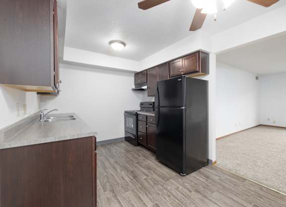A kitchen with a black fridge and wooden cabinets.