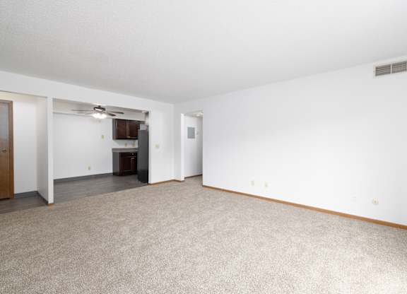 A spacious room with a carpeted floor and a ceiling fan.