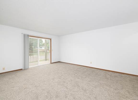 A room with a carpeted floor and a sliding glass door.
