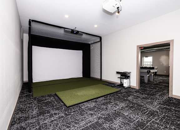A room with a white screen and a green mat on the floor.