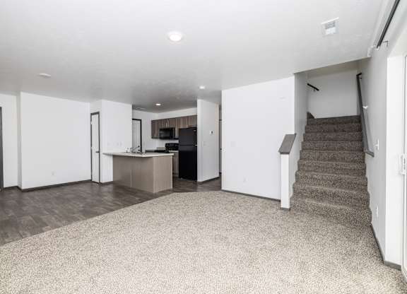 A spacious living room with a staircase leading to the upper floor.