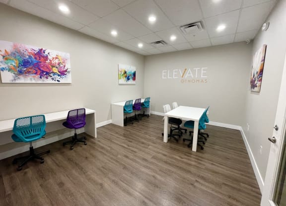 a room with a table and chairs and a sign that says elevate gyms on the wall