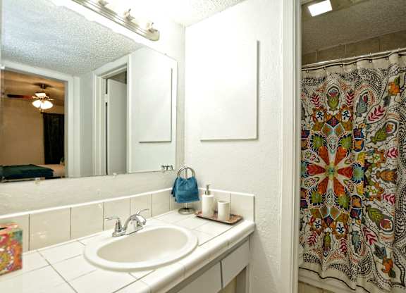 Bathroom with white vanity and colorful shower curtain at Azure Apartments, Texas, 78752