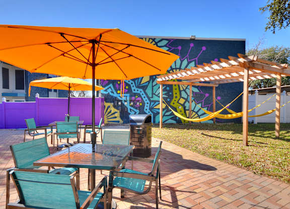 Outdoor patio with umbrellas and colorful murals at Azure Apartments, Austin, TX 78752