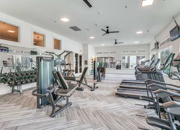 A gym with a variety of equipment including treadmills, weights, and exercise machines.