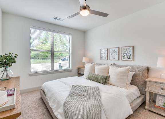 A well-lit bedroom with a large bed and a ceiling fan.