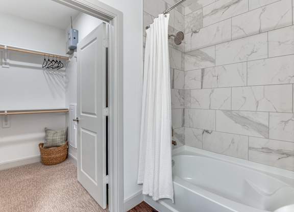 A white bathroom with a marble tile shower.