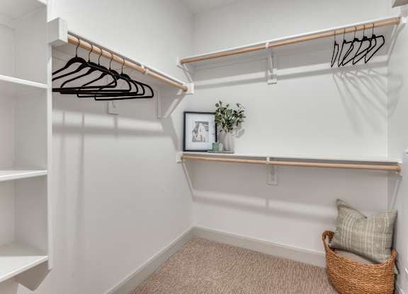 A white closet with a basket and a picture on the shelf.