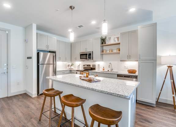 A kitchen with a white countertop and wooden stools.
