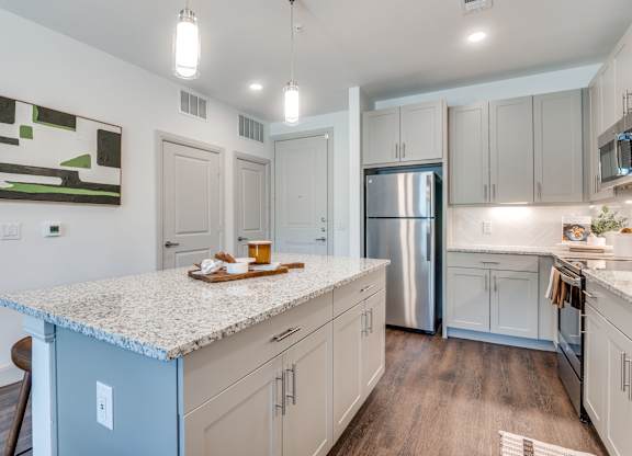 A kitchen with a granite countertop and stainless steel appliances.