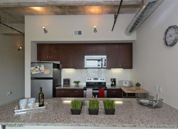 Modern kitchen with granite countertops and dark wood cabinets at 1221 Broadway Lofts Apartments, Texas