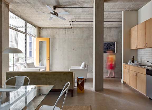 Open concept living space with exposed concrete at 1221 Broadway Lofts Apartments, San Antonio, TX 78215