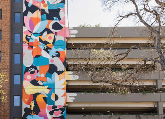 Outdoor courtyard with colorful mural and dining area at THE'68 Apartments, Texas