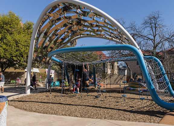 Modern playground with curved climbing structure at THE'68 Apartments, San Antonio, TX 78205