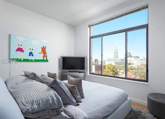 Bedroom with large window and city skyline views at THE'68 Apartments, San Antonio, TX
