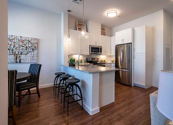 A kitchen with a bar area and a refrigerator. at Villas of Mason Hills, Texas