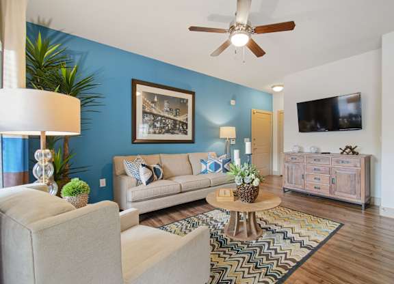 a living room with a blue accent wall and a ceiling fan at Alvista Round Rock, Round Rock, TX