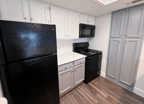 a kitchen with black appliances and white cabinets at Northchase, Austin, TX