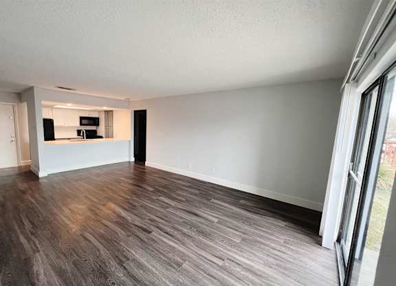 an empty living room with wood flooring and a kitchen at Northchase, Texas, 78753