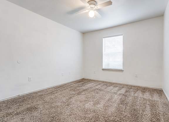 a bedroom with white walls and a ceiling fan at Rosillo Creek Apartments, Texas