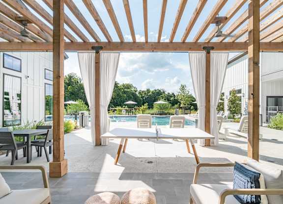 A wooden pergola over a patio with a table and chairs.
