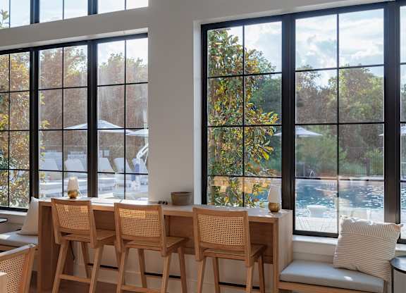 A room with a table and chairs by a window.