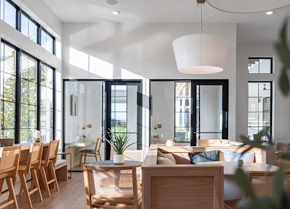 A modern dining room with wooden chairs and a white pendant light.