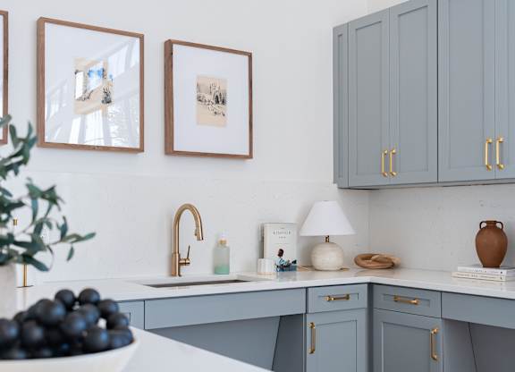 A kitchen with grey cabinets and a white countertop.