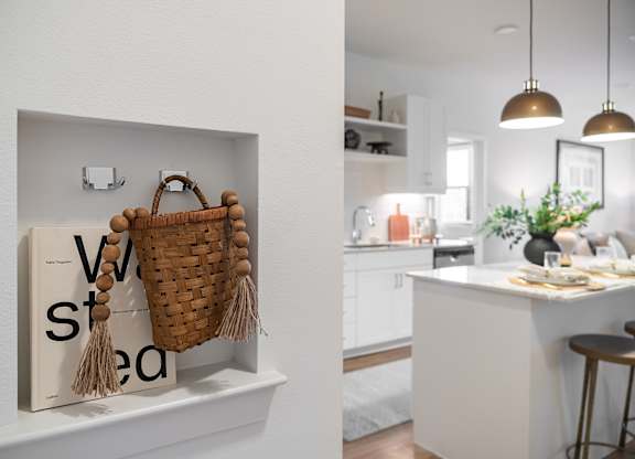 A kitchen with a white counter and a basket hanging on the wall.